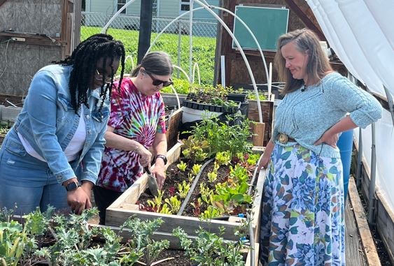 De’Anna Reed and Terri Burch work with Erin Dentice at a Hoop House garden bed.