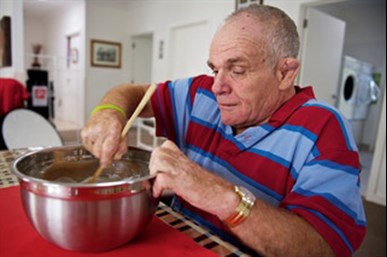 Elderly man stirring food in a bowl