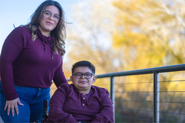 Mother and son together on bridge with trees behind them